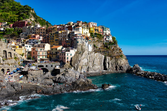 beautiful-shot-colorful-apartment-buildings-rocky-hill-seashore-blue-sky 1