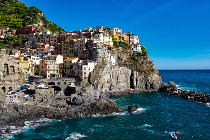 beautiful-shot-colorful-apartment-buildings-rocky-hill-seashore-blue-sky 1